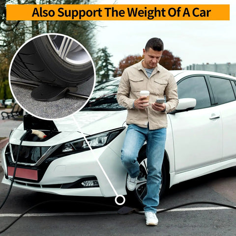 Man leaning on EV with coffee, using phone, foreground shows wheel on EV Charger Cable Protector For Garage Door Pass Through Built Tough Heavy Duty Cable Guard For Tesla All Models 3 Y X S And Mobile Connectors And Wall Chargers Stops Slips Bends Weather Wear And Trip Hazards.