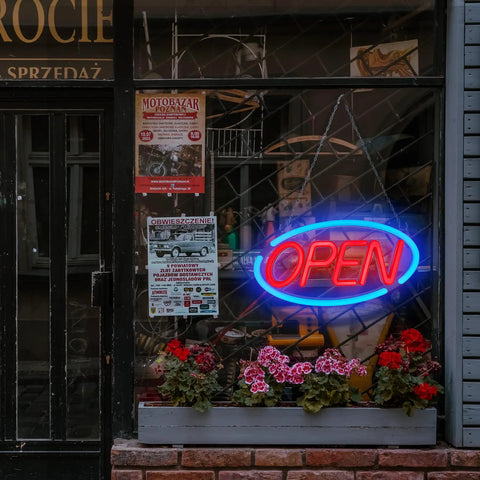 LED Open Sign For Business With Remote Control, Bright 24x12 Inch Window Sign For Restaurants Bars Retail Shops Salons And Storefronts, Blue And Red LED Neon Look, 12V Power Supply in storefront window with flowers below