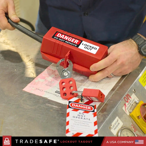 Heavy Duty 220 Volt Cord Lockout For Two Plugs Large Electrical Plug Lockout Device Industrial Grade Non Conductive Polypropylene OSHA Compliant Red Lockout Tool For Energy Isolation in use on a workbench by a person securing two plugs with danger tag visible.