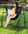 Woman sitting in 2 In 1 Hammock With Stand For Outdoors Portable Heavy Duty Steel Frame Supports Up To 480 Lbs Easy Setup In Minutes Black Multi Functional Swing Chair, using a laptop in a garden setting.