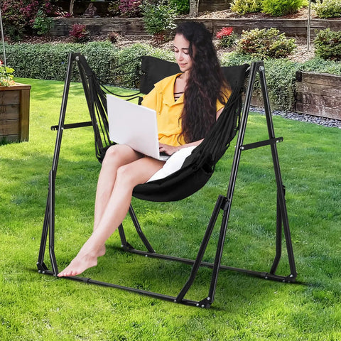 Woman sitting in 2 In 1 Hammock With Stand For Outdoors Portable Heavy Duty Steel Frame Supports Up To 480 Lbs Easy Setup In Minutes Black Multi Functional Swing Chair, using a laptop in a garden setting.