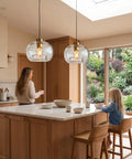 CASAMOTION Glass Pendant Lights, Textured Clear Globe Shade hanging over a kitchen island with a woman and child.