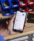 Portable Industrial Label Printer With Bluetooth And Pro Label Tool App Hands Free Belt Clip For Tight Jobsite Spaces Rechargeable Battery Prints Durable Labels Up To 1 Inch Industrial Formats, in use on a workbench.