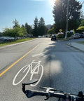 Big Bar End Mirror For E Bikes With Automotive Grade Glass Delivers Crystal Clear View On Left Or Right Fits Most 14.8 To 23 Mm Handlebars Wide Opening No Glare Blast Resistant Safety Mirror For Your Ride featuring a handlebar view on a sunny road with clear bike lane marking.