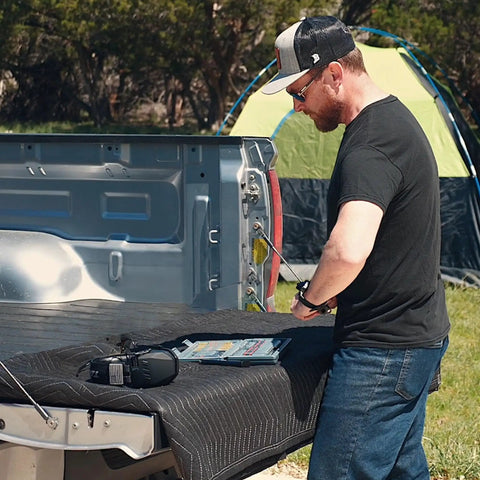 Man using Pin Punch Set 40 Piece Steel And Brass With Hammer And Bench Block for mechanical repair on truck tailgate outdoors.