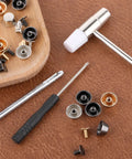 Top Tier Brass Purse Feet For Handbags And Totes - Screw Back Badass Bottom Guards With Punch And Driver Kit Included - assorted brass studs and tools on a work surface