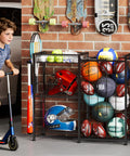 All In One Sports Gear Organizer Cart With Elastic Straps And Removable Basket For Garage Organization, Ball Storage Rack for basketballs, soccer balls, and more with toy gear hooks, black, in a garage setting with various equipment.