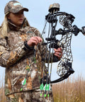 Person in camouflage holding a compound bow in a field