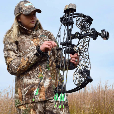 Person in camouflage holding a compound bow in a field