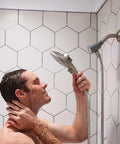 Person holding Spot Resist Brushed Nickel Six Function Five And A Half Inch Handheld Showerhead With Magnetic Docking System And Quick Release Hose