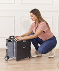 Woman adjusting collapsible rolling storage cart on wheels for home office classroom use mobile organizer with retractable handle.