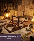 Medieval Catapult STEM Building Kit wooden model on table with candles and historical schematics.