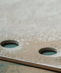 Beige ceramic tile sample with two round drilled holes