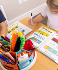 Rotating Art Supply Organizer With Six Colorful Cups That Holds Crayons Markers And Pencils Kid Friendly Desk Caddy For Classroom Or Home Use Easy Grab And Go Access on a table with kids drawing.