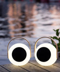 Two Eye Color Changing LED Lantern With 10W Bluetooth Speaker on a wooden deck by water, outdoor white mood lamp setting.