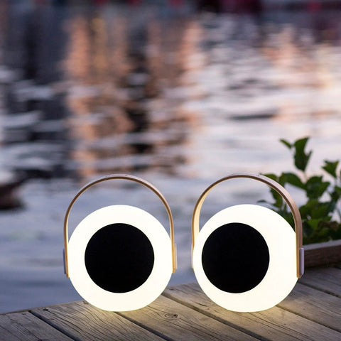 Two Eye Color Changing LED Lantern With 10W Bluetooth Speaker on a wooden deck by water, outdoor white mood lamp setting.