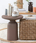 Stylish living room with modern brown table and woven ottoman, featuring books and a decorative vase on top.