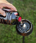 Pouring BiteFighter Mosquito Repellent Torch Fuel 64 Oz Citronella Cedar Formula for mosquito defense into torch outdoors