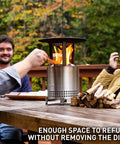 Mesa XL Heat Deflector With 3 Detachable Legs for Fire Pit showing stainless steel build next to people on outdoor patio