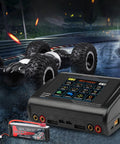 Dual RC Battery Charger With Touch Screen Beefy Power 200W AC Or 400W DC next to RC car and battery on race track