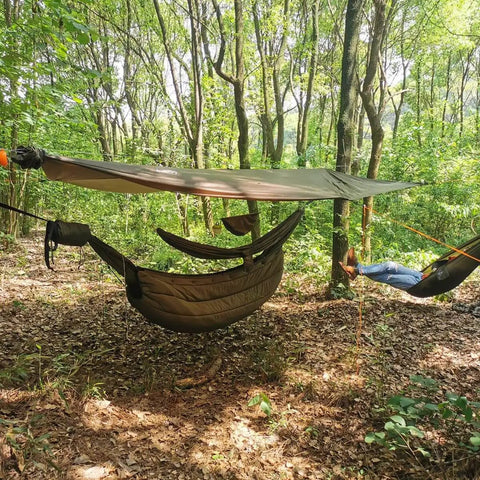 Snakeskin Tarp Sleeve 12ft Camping Rain Fly Storage Kit covering hammock in forest, OD Green, for hiking and backpacking.