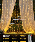 Warm White 300 LED Curtain Lights With 10 Strands, 9.8Ft By 9.8Ft Fairy String Lights For Bedroom And Window Wall Decor, 8 Modes With Memory Function, Plug In Not Connectable, Great For Christmas Parties And Weddings glowing around a table.