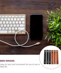 Six Piece Slick Leather Cable Straps For Usb Gadgets And Headphones Black Anti Tangle Wire Ties on a desk with keyboard and phone.