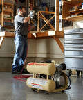 Man using the 2 HP Portable Twin Stack Air Compressor for shop work in a garage setting with tools around.