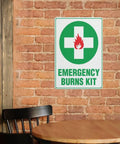 Emergency Burn Care Sign 8x12 Inches Aluminum Warning Plate on brick wall, showing green cross and fire symbol, for safety reminder.