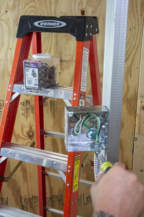 Electrician installing 3/8 In Flex 90 Degree Connector For FMC Metal Clad And Armored Cable To Steel Outlet Box Secure Bonding