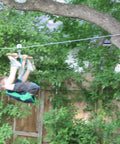A child using a zip line attached to a Beefy Stainless Steel Cable Three Eighths Inch By 100M Heavy Duty Wire Rope in a backyard setting.