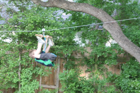 A child using a zip line attached to a Beefy Stainless Steel Cable Three Eighths Inch By 100M Heavy Duty Wire Rope in a backyard setting.