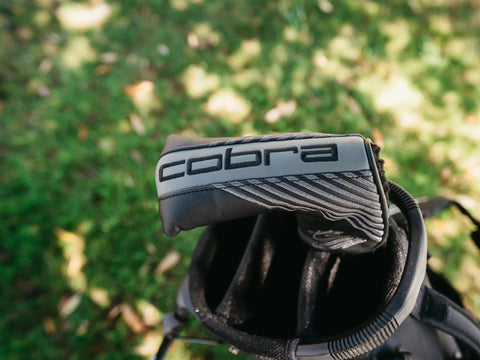 Classic Blade Putter With CNC Machined Face For Precision, Soft Feel And Tour Inspired Alignment in golf bag on grassy field.