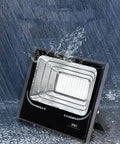 JUDYSSY 25W Led Dusk to Dawn Solar Flood Light in rain, showcasing waterproof design and built-in reflector, suitable for outdoor use.