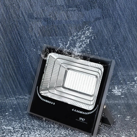 JUDYSSY 25W Led Dusk to Dawn Solar Flood Light in rain, showcasing waterproof design and built-in reflector, suitable for outdoor use.
