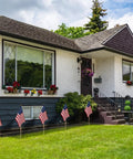 Pack Of 12 12X18 Inch Outdoor American Flags On Sticks With Vivid Color displayed in front yard of a house, showing patriotic decor.