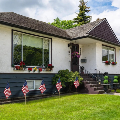 Pack Of 12 12X18 Inch Outdoor American Flags On Sticks With Vivid Color displayed in front yard of a house, showing patriotic decor.
