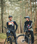 Two mountain bikers on a forest trail with bikes equipped with Front Bike Fender For Face And Suspension Fork Protection