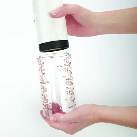Two Cup Adjustable Measuring Cup with Grippy Rotating Body, silicone disc, inner track, held between hands.