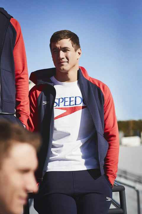 Man in navy and red zip-up jacket outdoors, suitable for training and travel.