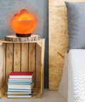 Fire Bowl Salt Lamp With Crystal Massage Balls Handcrafted From Pakistan on a wooden shelf near a bed, calming glow