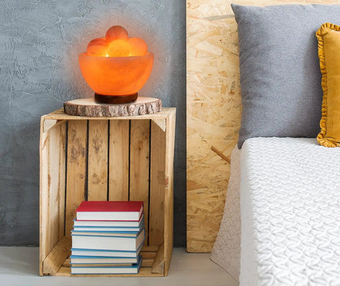 Fire Bowl Salt Lamp With Crystal Massage Balls Handcrafted From Pakistan on a wooden shelf near a bed, calming glow