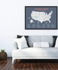 National Parks Map Poster With All 63 U S Parks Updated Edition framed above a light grey sofa in a modern living room setup.