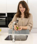 Woman using Silicone Sink Splash Guard with Non Slip Suction Base for kitchen, preventing water on clothes, gray color