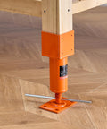 Orange adjustable screw jack post with square base plate under a wooden beam; leveling floor jack with crossbar handles