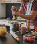 Person using Wooden Salt And Pepper Grinder Set Refillable Mills With Adjustable Coarseness Crafted From Solid Acacia Wood With Ceramic Core