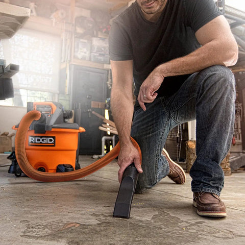 Heavy Duty Wet Dry Vacuum And Blower With 12 Gallon Capacity And 5 Peak Horsepower Detachable Leaf Blower Head For Workshop Cleanup in use on garage floor.