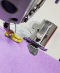 Magnetic seam guide sewing machine accessory on purple presser foot guiding purple fabric