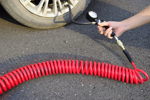 Heavy Duty Polyurethane Recoil Air Hose Self Coiling Compressor Line 1/4 In By 25 Ft connected to a tire pressure gauge.