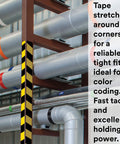 Industrial setting showing pipes with black and yellow striped vinyl floor marking tape for safety and color coding.